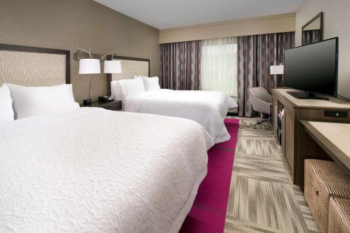 路易斯威尔Hampton Inn Louisville East Hurstbourne的酒店客房设有两张床和一台平面电视。