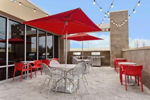 阿伯丁巴尔的摩/亚伯丁MD希尔顿欣庭套房酒店的一个带桌椅和红色遮阳伞的庭院