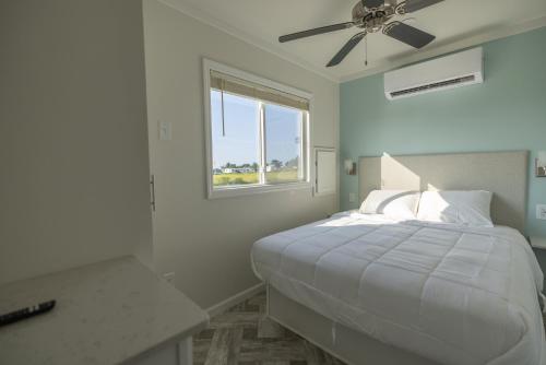 钦科蒂格Blufin Bungalows & Marina的白色卧室配有一张带吊扇的床