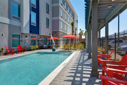 巴拿马城海滩Home2 Suites By Hilton Panama City Beach, Fl的一座带桌椅的游泳池以及一座建筑
