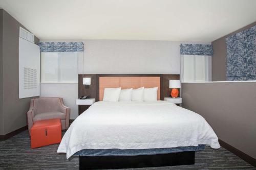 丹佛丹佛市中心汉普顿套房旅馆的酒店客房带一张大床和一把椅子
