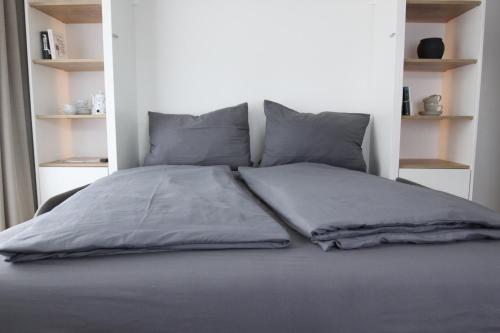 博尔库姆Inselbutze Borkum的一张带灰色床单和枕头的床