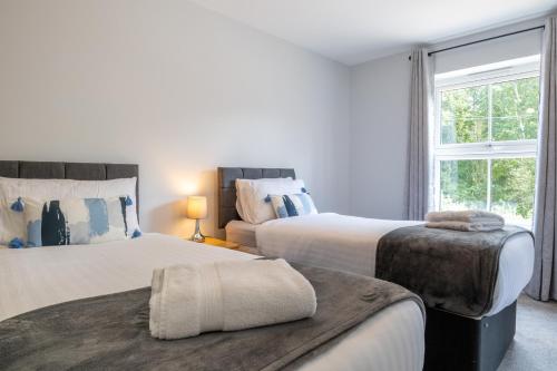 特伦特河畔伯顿Amazing 5bed, Free Parking Short and long term stays的一间卧室设有两张床和窗户。