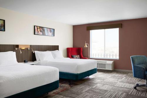 拉斯维加斯拉斯维加斯亨德森希尔顿花园酒店的酒店客房,设有两张床和一张红色椅子