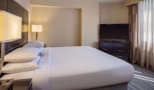 明尼阿波利斯DoubleTree Suites by Hilton Minneapolis Downtown的卧室配有一张白色大床和一台平面电视。