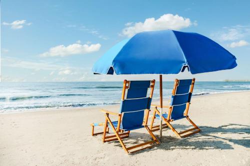 默特尔比奇Homewood Suites by Hilton Myrtle Beach Oceanfront的海滩上的两把椅子和一把遮阳伞
