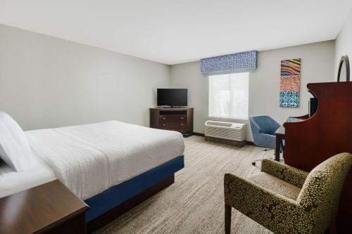 西萨克拉门托西萨克拉门托汉普顿旅馆及套房酒店的配有一张床和一把椅子的酒店客房