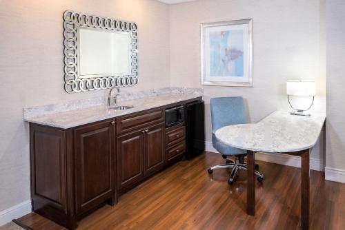 夏洛特Hampton Inn & Suites South Park at Phillips Place的一间带水槽、桌子和镜子的浴室