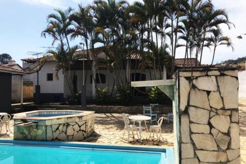 伊塔年杜Casa de campo com piscina, mesa de bilhar e 3 quartos的一座带游泳池和棕榈树的房子