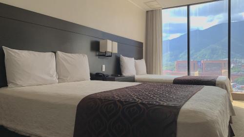 加拉加斯HOTEL CHACAO SUITES的酒店客房设有两张床和大窗户。
