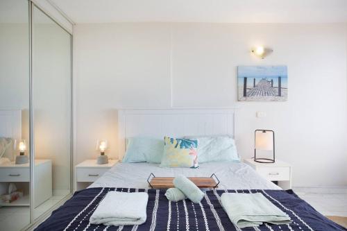 悉尼'Bondi Fairview' Coastal Panorama with Balcony的白色卧室,配有带毛巾的床