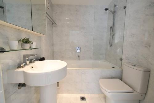 悉尼Resort-style Coastal Living with Balcony & Pool的浴室配有盥洗盆、卫生间和浴缸。