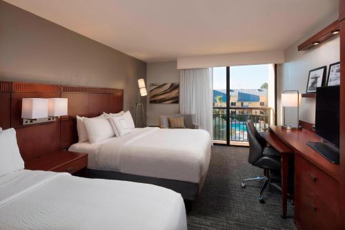 波因顿海滩伯恩顿海滩万怡酒店的酒店客房设有两张床、一张桌子和一台电视。