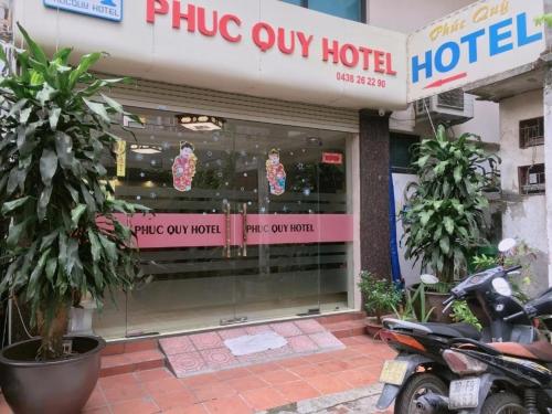 河内Phúc Quý Hotel - 149B Lê Duẩn - by Bay Luxury的停在酒店前的一间商店,外面停有一辆摩托车