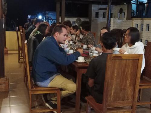 姆杜克KARANG SARI Guesthouse的一群坐在餐厅桌子上的人