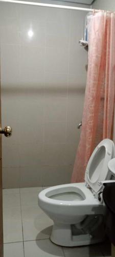 马尼拉Place to stay的浴室设有白色卫生间和粉红色的淋浴帘