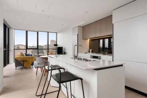 悉尼Urban Rest North Sydney Apartments的厨房配有白色的台面、椅子和台面