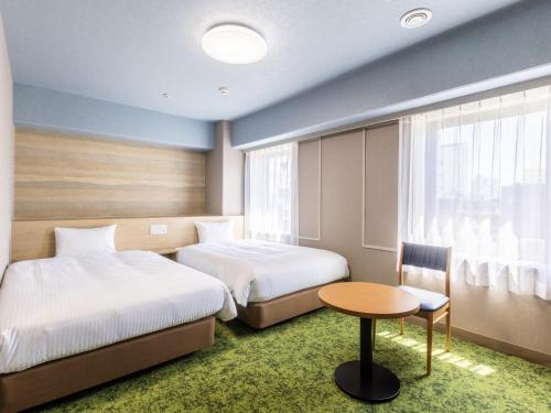 静冈Hotel Wing International Shizuoka的酒店客房设有两张床和一张桌子。