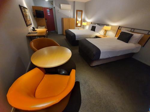 奥克兰外百老汇汽车旅馆的酒店客房设有两张床、一张沙发和一张桌子。