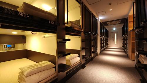 大阪Acro Capsule Hotel Namba Dotonbori的带几张双层床和走廊的客房