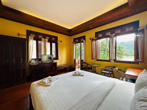 琅勃拉邦Villa Phonethip Mekong Riverside的一间卧室设有一张大床,拥有黄色的墙壁和窗户。