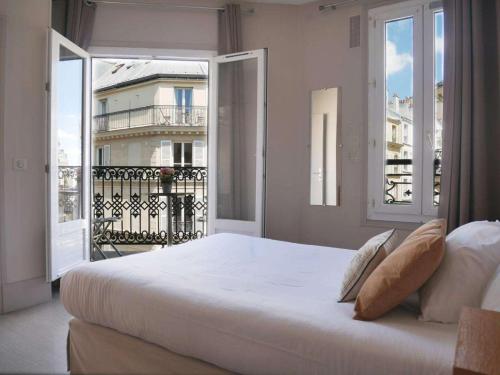 巴黎美妙停留酒店的一间带一张白色大床的卧室和一个阳台