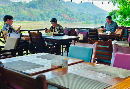 琅勃拉邦Villa Phonethip Mekong Riverside的一群坐在餐厅桌子上的人