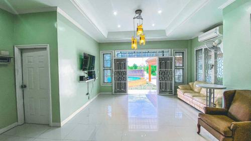 七岩พูลวิลล่าชะอำ Amazia Pool Villa的客厅设有绿色的墙壁、沙发和电视