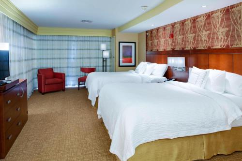 诺布尔斯维尔印第安纳波利斯诺布尔斯维尔万怡酒店的酒店客房,设有两张床和一张红色椅子