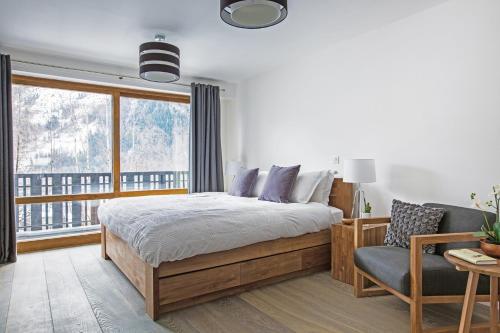 夏蒙尼-勃朗峰Le Brevent 3 Apartment的卧室配有床、椅子和窗户。
