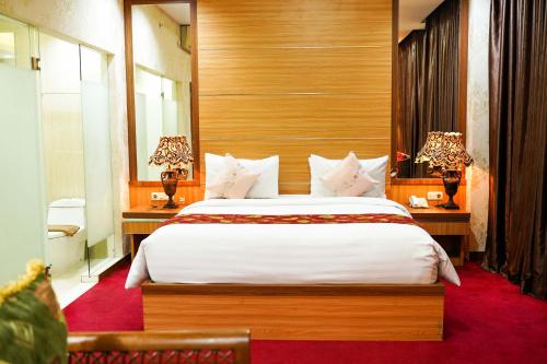 DukuGrand Buana Lestari Hotel的一间卧室配有一张大床和两张带台灯的桌子。