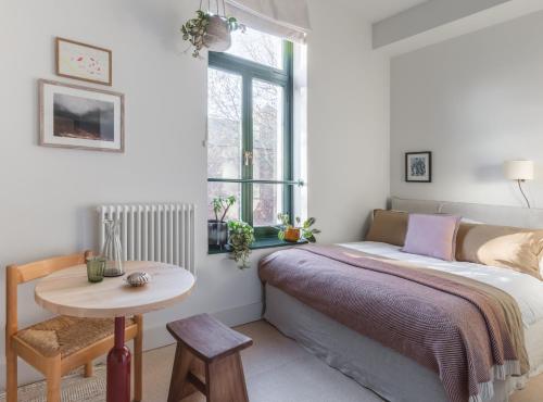 伦敦Mason & Fifth, Bermondsey的一间卧室配有一张床、一张桌子和一个窗户。