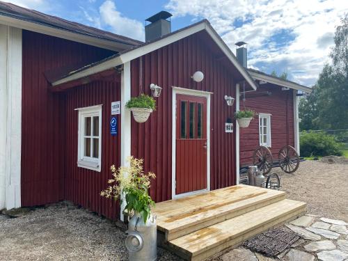 HyrynsalmiLaattajan Pirtti vuokramökki 1-5 henkilölle的红色的房子,设有木门廊和长凳