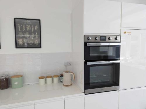 伯恩茅斯Cosy Bee的厨房配有黑烤箱和白色橱柜。