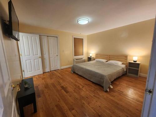 联城Classy 3 bed near NYC with view!的一间卧室配有一张床、木地板和两盏灯。