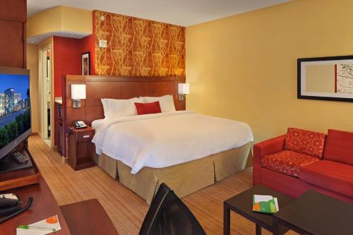 CoatesvilleCourtyard Philadelphia Coatesville Exton的酒店客房设有一张大床和一张红色沙发。