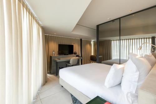 波尔图Porto Royal Bridges Hotel的酒店客房配有一张床、一张书桌和一台电视。