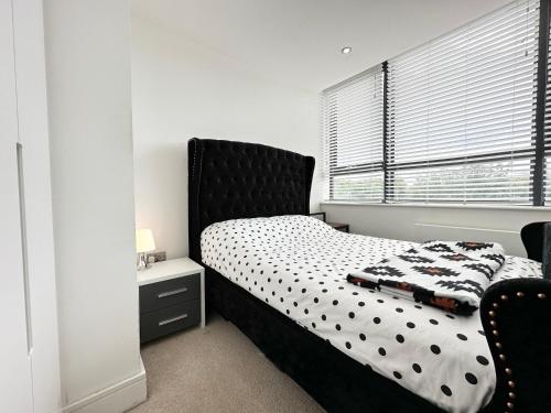 海华德希思Cosy Apartment Haywards Heath的一间卧室配有一张带黑色床头板的床和窗户