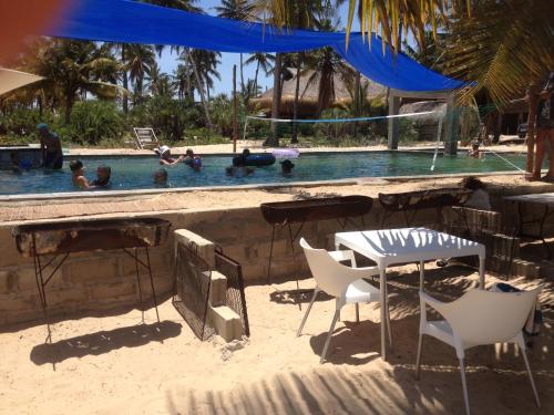 伊尼扬巴内Barra Dica - CAMPING的游泳池附近的沙滩上摆放着桌椅