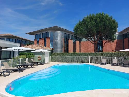 图卢兹Appart'City Confort Toulouse Purpan的大楼前的大型蓝色游泳池