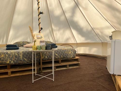 BlesdijkeGlamplodge met privé sanitair的一间卧室配有一张床,帐篷内配有一张桌子