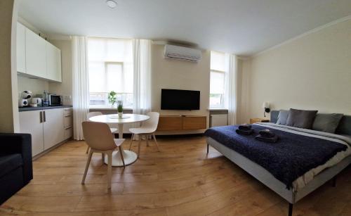 采西斯Cēsu apartamenti的一间卧室配有一张床铺和一张桌子,还设有一间厨房