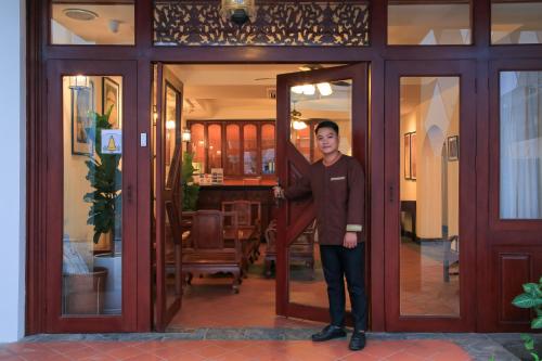 万象Phongsavath Boutique Hotel的站在房子门口的人