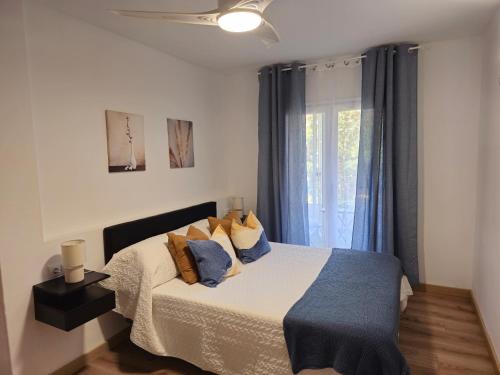 艾姆布里亚布拉瓦Apartamento El olivo的一间卧室配有一张带蓝色枕头的床和一扇窗户。