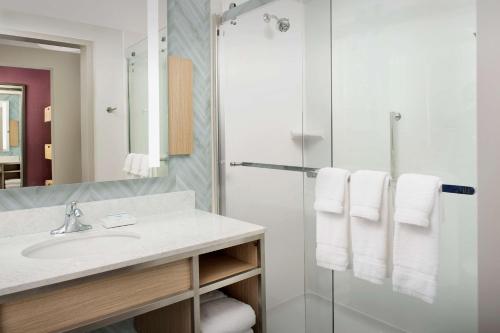 奥兰多Hilton Garden Inn Orlando Downtown的浴室配有盥洗盆、淋浴和毛巾