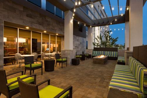 钱德勒凤凰城钱德勒希尔顿欣庭套房酒店的庭院设有桌椅和壁炉。