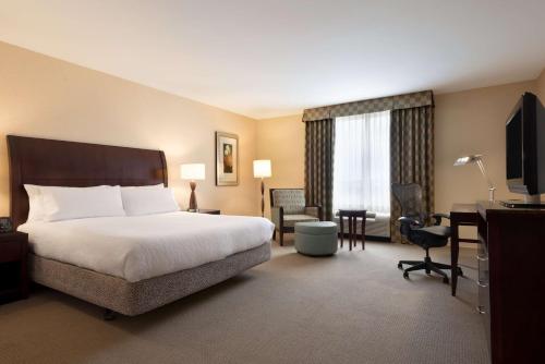 阿什本杜勒斯北希尔顿花园旅馆的酒店客房配有一张床、一张书桌和一台电视。