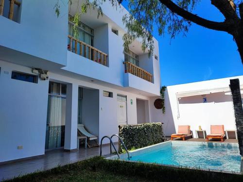 帕拉卡斯Paracas Guest House的一座别墅,在一座建筑前设有一个游泳池