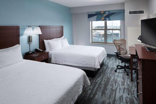 俄克拉何马城俄克拉荷马城布里克汉普顿套房酒店的酒店客房设有两张床、一张桌子和一台电视。