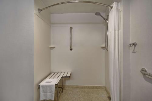 皇后区Hampton Inn NY-JFK的白色的浴室设有长凳和淋浴。